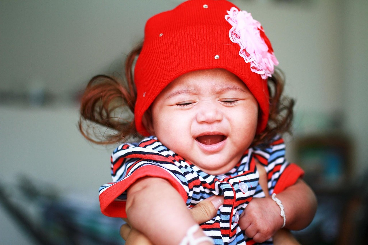 A kid crying with a red hat on their head 
