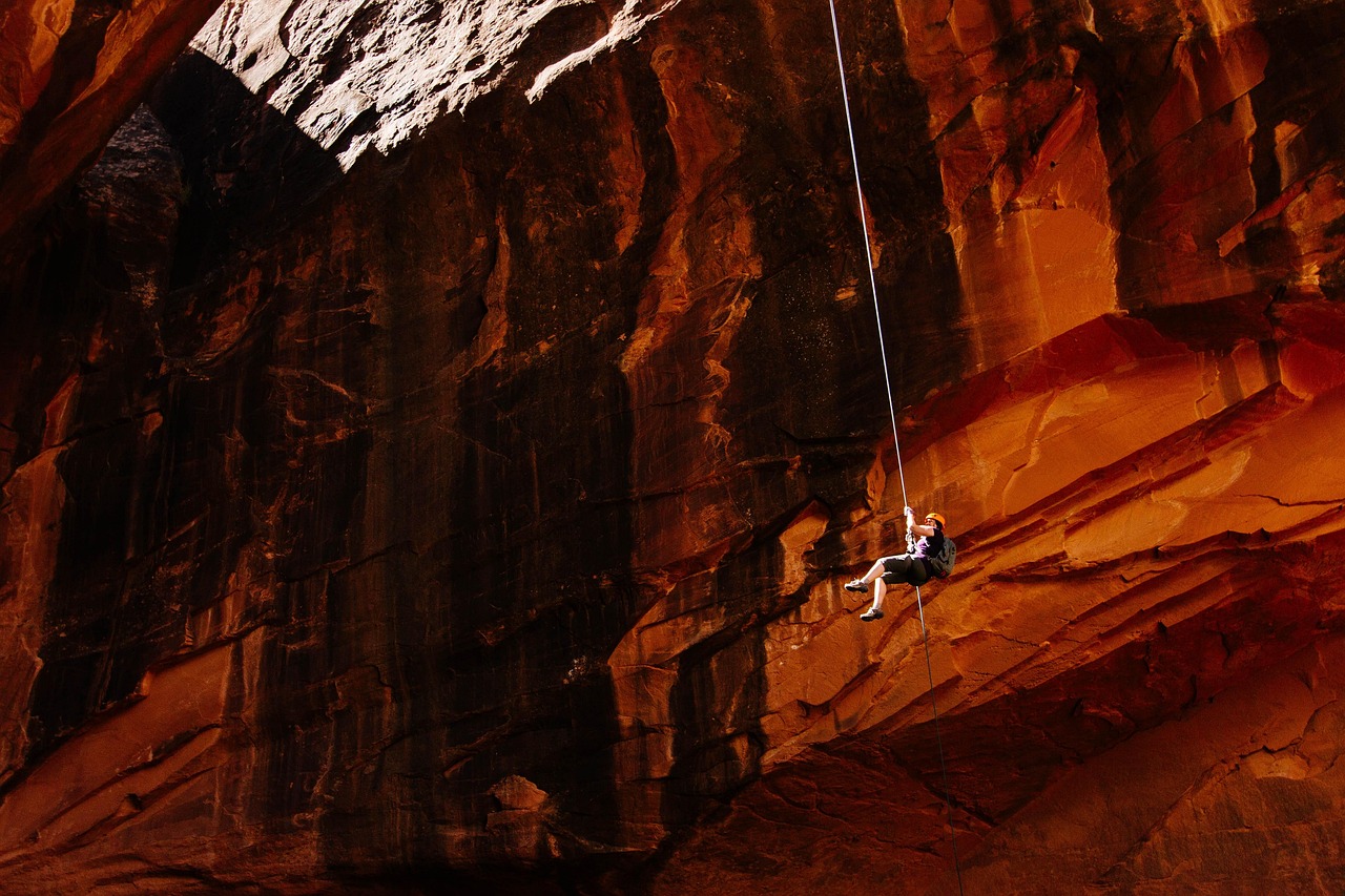 Someone hanging on a rope off of a mountain with a backpack on their back
